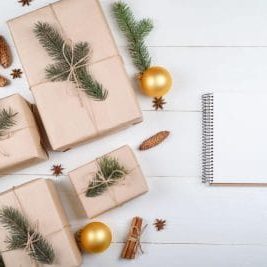 Ideias de presentes de Natal com cadernos, papelaria e um presente embrulhado