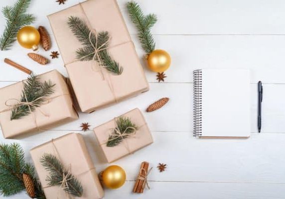 Ideias de presentes de Natal com cadernos, papelaria e um presente embrulhado